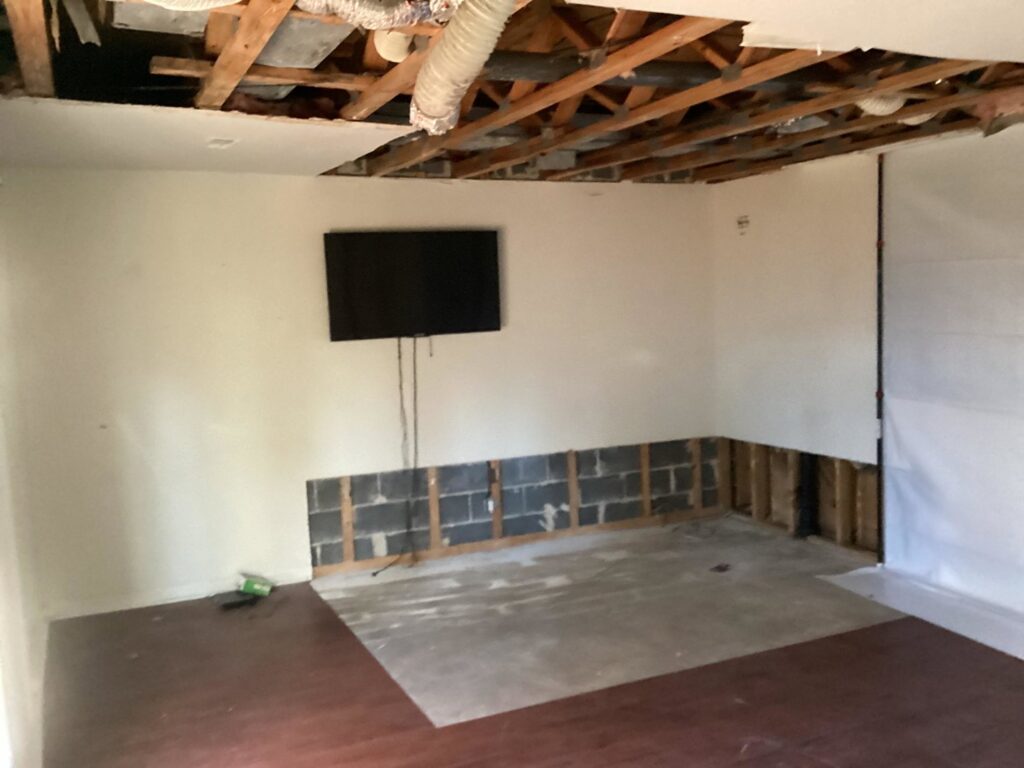A room undergoing water damage remediation with exposed ceiling joists and damaged lower walls by Doctor Fix-It in Denver, CO.