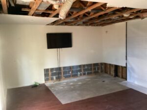A room undergoing water damage remediation with exposed ceiling joists and damaged lower walls by Doctor Fix-It in Denver, CO.