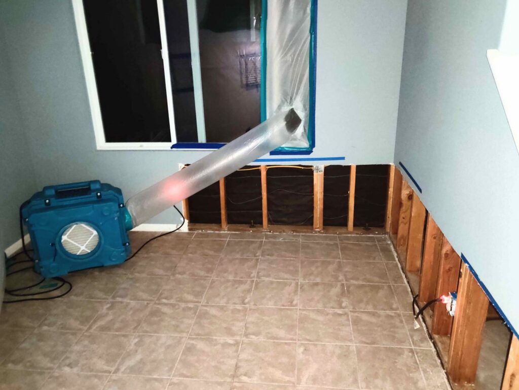 A room undergoing water damage remediation with walls removed and drying equipment in use by Risk Free Serv San Diego, CA