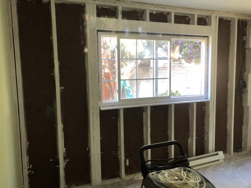 A room undergoing water damage remediation with walls stripped down to the studs, showing the restoration process by One Call Services of Oakland in Oakland, CA.