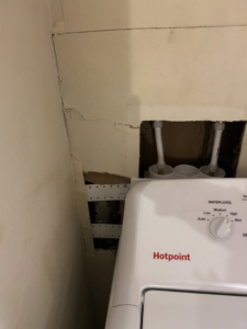 Wall opened for water damage repair behind a washing machine by Exterior Repair Medics in Manhattan, KS.
