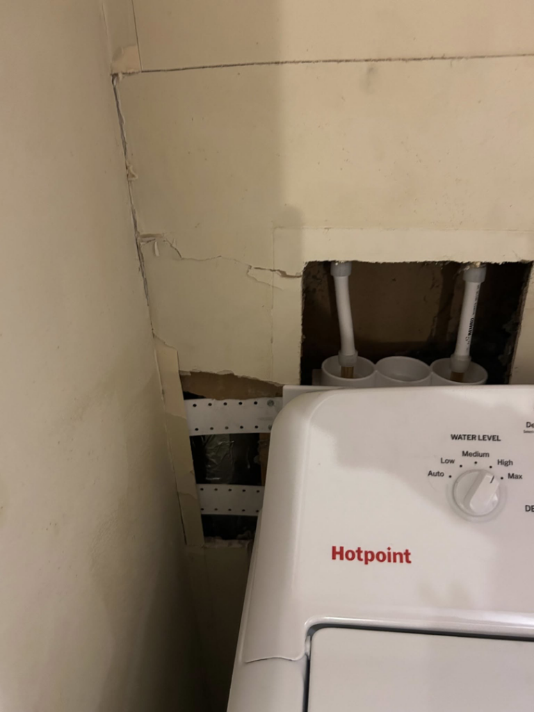Wall opened for water damage repair behind a washing machine by Exterior Repair Medics in Manhattan, KS.