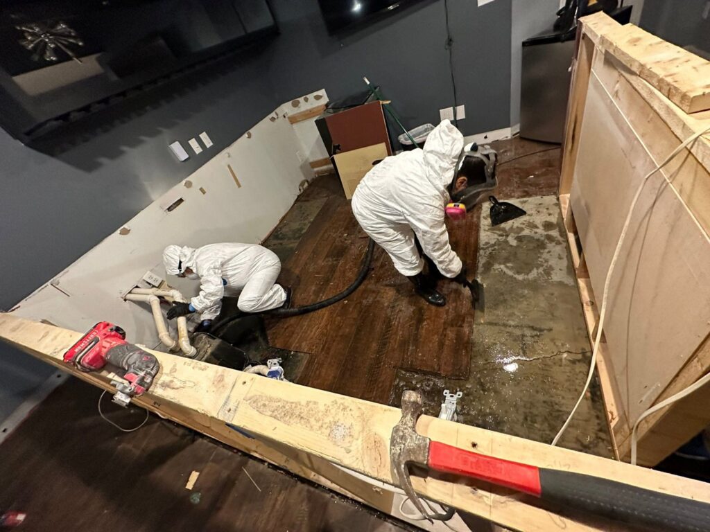 A water damage restoration crew removing damaged flooring in a home for Guardian Angel Restoration in Noblesville, IN