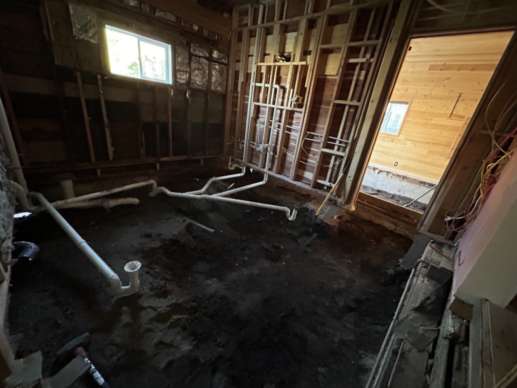 An interior room undergoing water damage restoration demolition with exposed earth and new plumbing by HomeTown Construction and Restoration LLC in Anaconda, MT