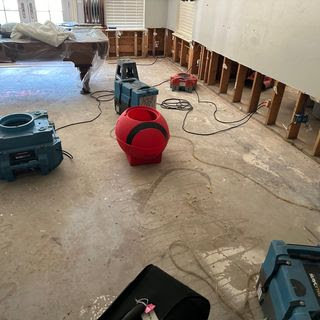 A room with exposed studs and concrete floor, featuring multiple drying machines for water damage restoration by Paul Davis of Norman & SW OKC in Norman, OK.