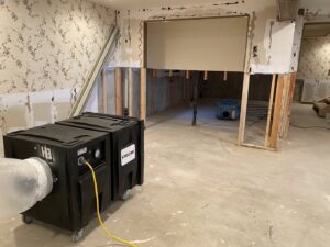 Water damage restoration equipment, including a large air mover, drying out a room with removed drywall at Anytime Flood Restoration in Thornton, CO