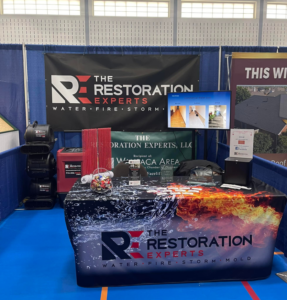 A display booth featuring water damage restoration equipment and branding for The Restoration Experts in Waupaca, WI.