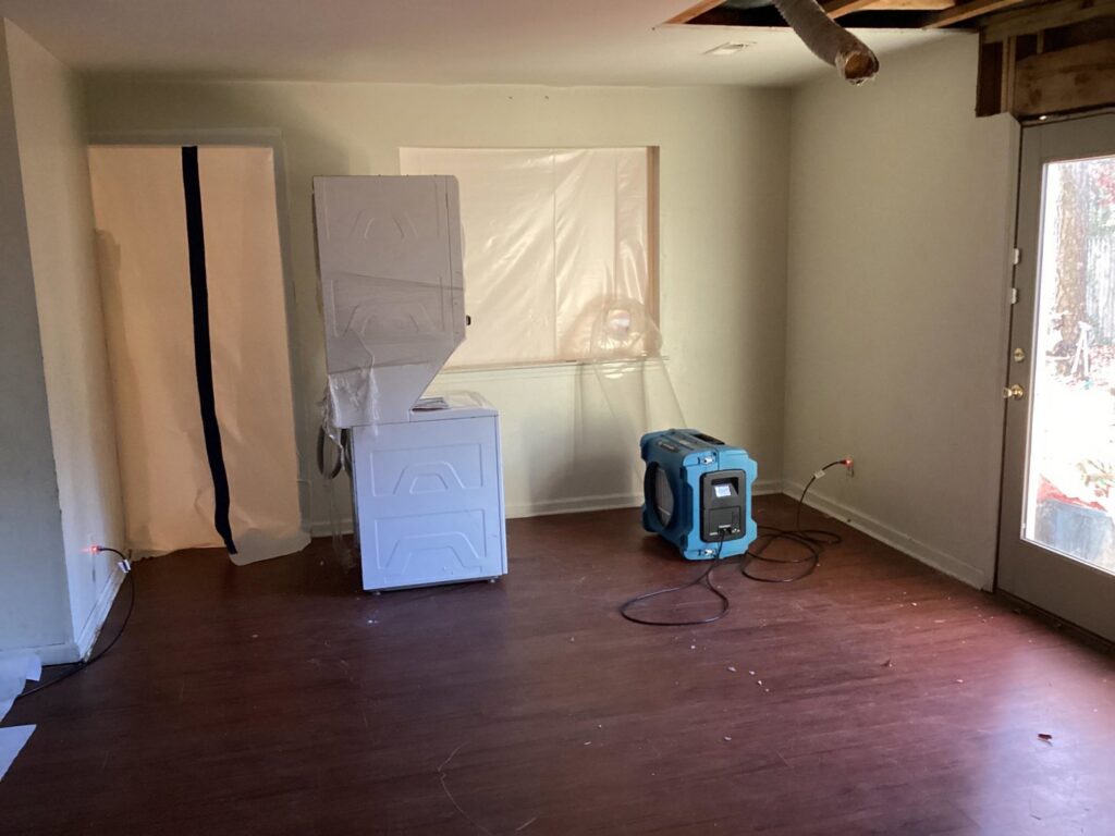 A room undergoing water damage restoration with a dehumidifier, air mover, and plastic sheeting by Doctor Fix-It in Denver, CO.