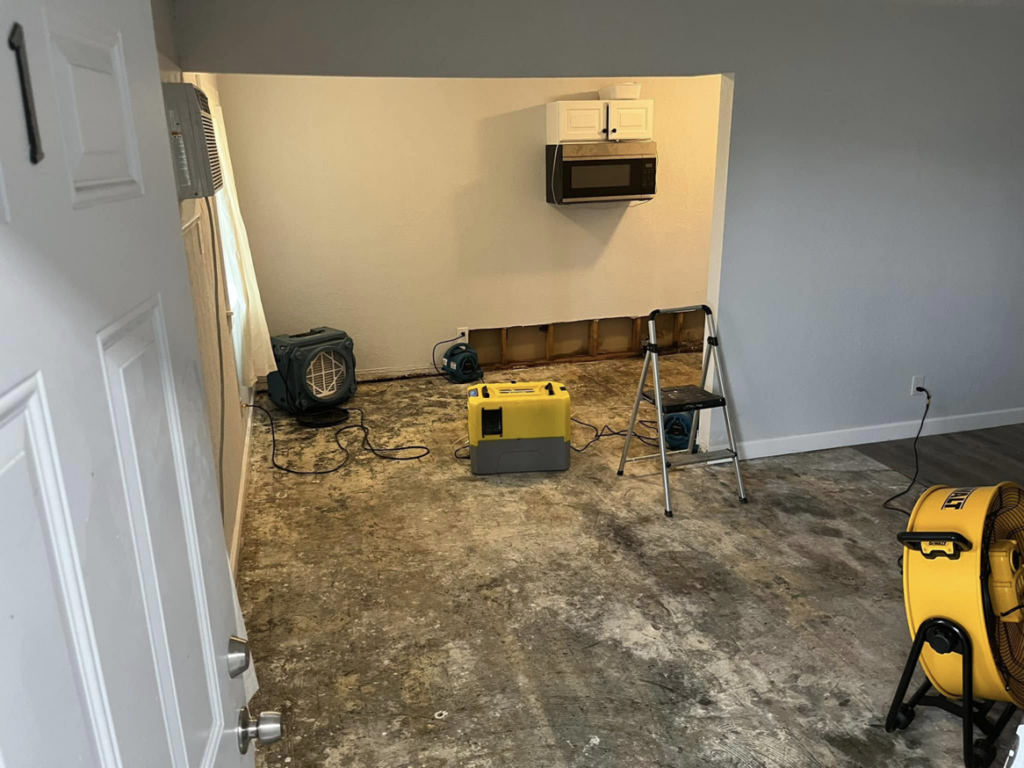 Water damage restoration equipment, including fans and dehumidifiers, in a room being dried by Highland Restoration in Hampton, VA