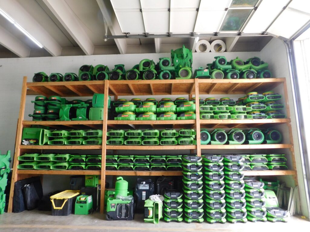 Shelves stocked with green air movers and dehumidifiers, essential water damage restoration equipment at Servpro of East Independence/Blue Springs in Oak Grove, MO.