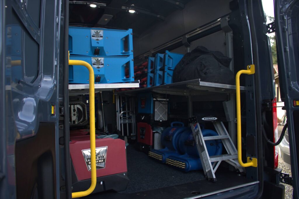 Interior of a work van fully stocked with professional water damage restoration equipment for The Recover Tech Restoration in Vancouver, WA.