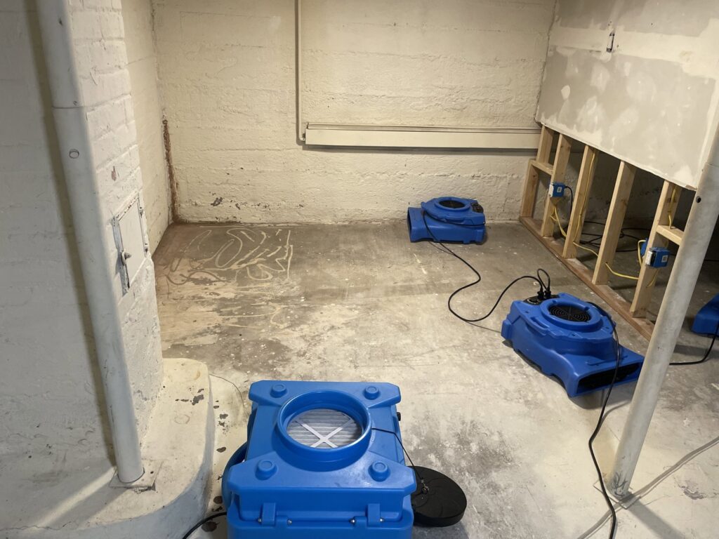 Water damage restoration in progress with multiple drying fans and exposed wall studs by North Shore Restore in Duluth, MN