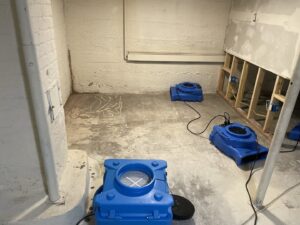 Water damage restoration in progress with multiple drying fans and exposed wall studs by North Shore Restore in Duluth, MN