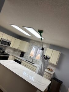 A water damage specialist from Property Doctors, Inc. in Denver, CO, cleaning a kitchen ceiling in a hazmat suit.