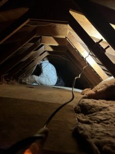 A Gold Star Services LLC water damage specialist in a hazmat suit working in an attic in Newark, DE