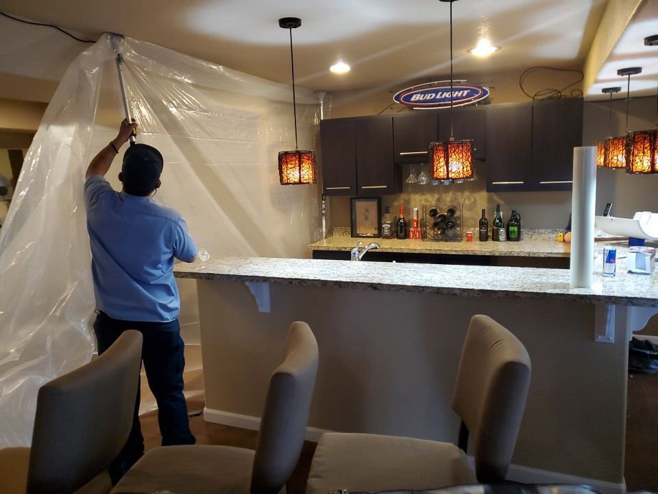 A Water Damage, Inc. specialist setting up plastic containment sheeting in a kitchen area in Denver, CO.