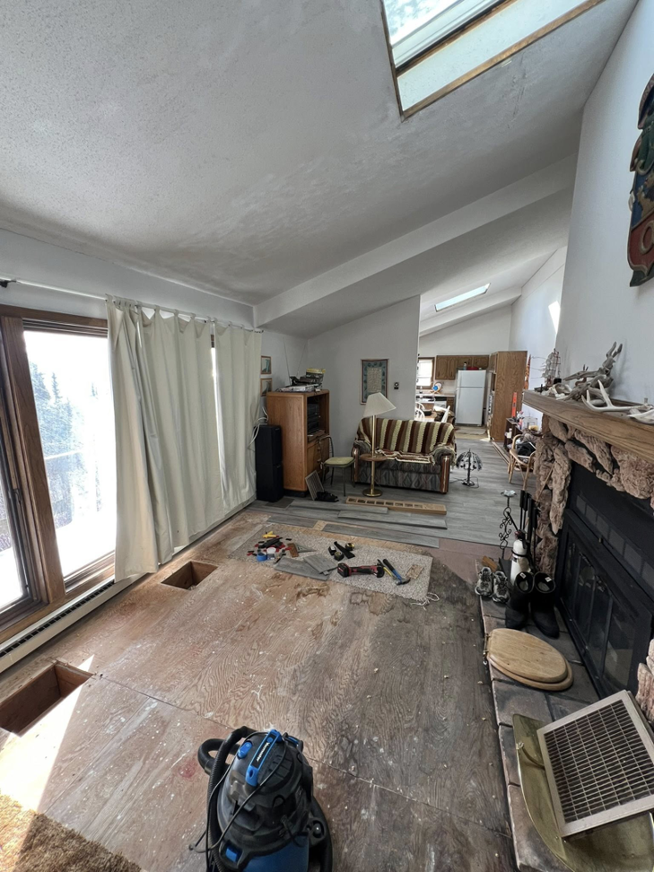 A room with water-damaged carpet removed, exposing the subfloor and a shop vac for drying by Agate Bay Restoration in Two Harbors, MN.