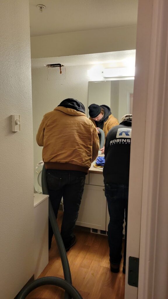 A team of water damage specialists from Robinson Restoration working in a bathroom during a restoration project in Vancouver, WA