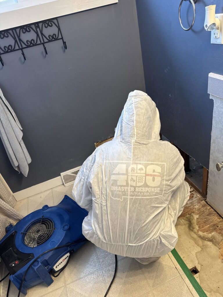 A water damage technician from 406 Disaster Response using an air mover to dry a damaged bathroom floor in Billings, MT.