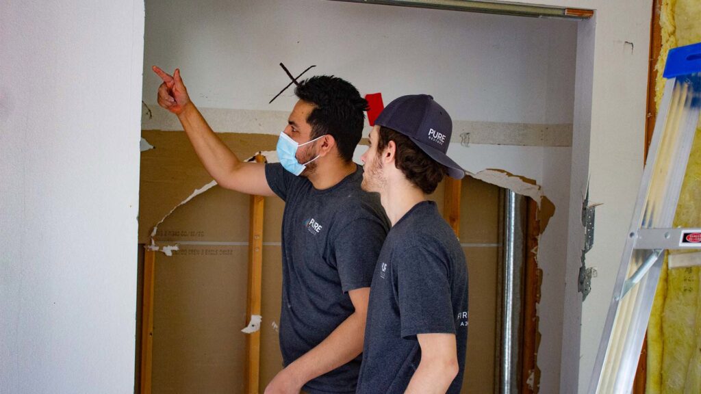 Pure Restore technicians inspecting a damaged wall during a water damage assessment in Northglenn, CO.