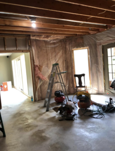 A water-damaged basement undergoing repair with exposed insulation and equipment by Tules Remodeling LLC in Olathe, KS