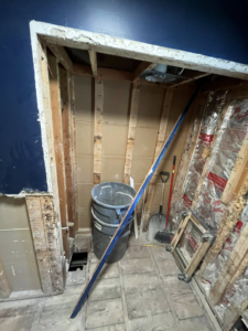 A bathroom undergoing demolition after water damage, with walls removed to studs by 24K Restoration in Flint, MI.