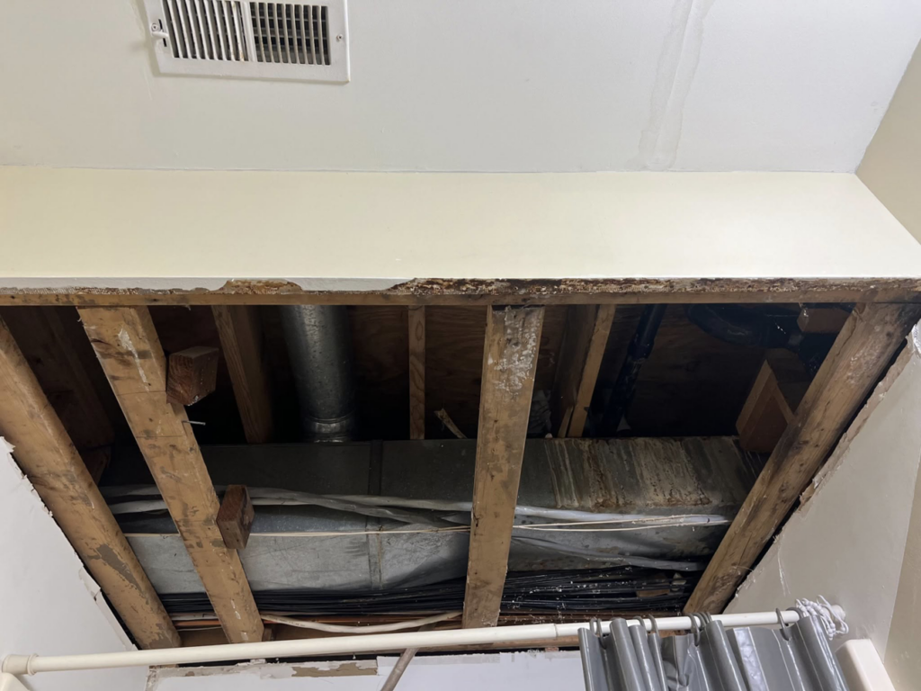 Water-damaged ceiling with exposed beams and ductwork during repair by Exterior Repair Medics in Manhattan, KS.