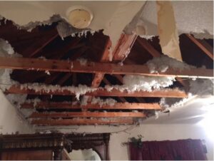 A severely water-damaged ceiling with exposed insulation and wooden beams, a restoration project for SO-CO Water Damage in Pueblo, CO.
