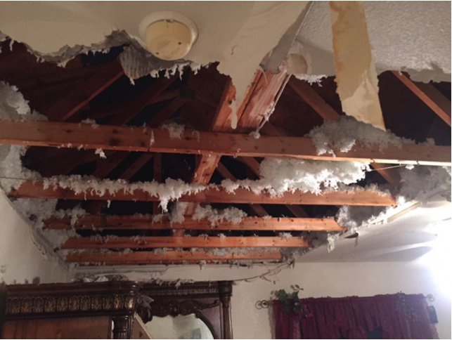 A severely water-damaged ceiling with exposed insulation and wooden beams, a restoration project for SO-CO Water Damage in Pueblo, CO.