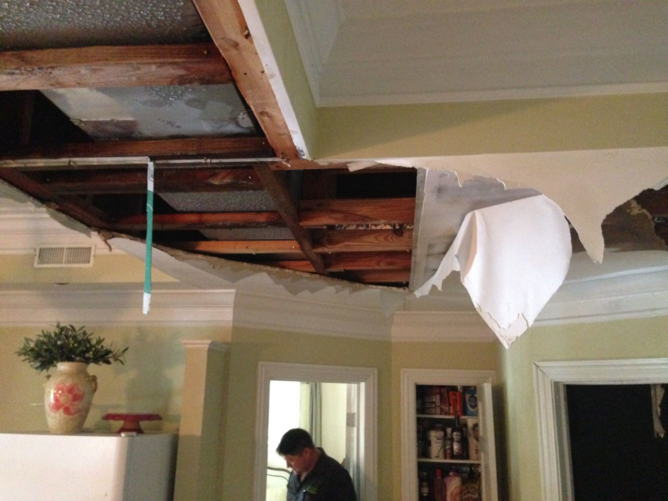 A technician from PDE - Property Damage Experts inspecting a severely water-damaged ceiling in a home in Birmingham, AL.