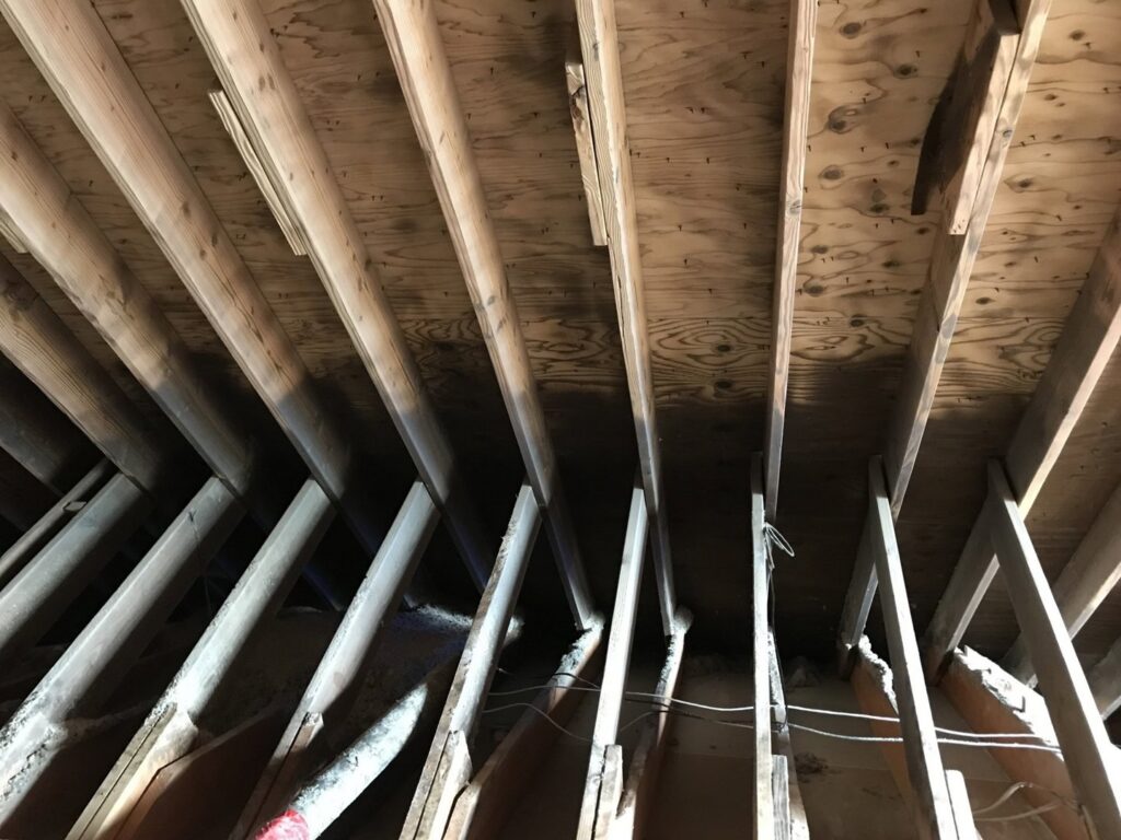 Dark stains on wooden ceiling joists indicating water damage, a common issue addressed by JP Maguire Associates in Waterbury, CT.