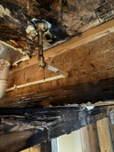 A severely water-damaged ceiling with leaking pipes and visible mold, indicating a water damage specialist job by Catalyst Restoration in Hagerstown, MD.