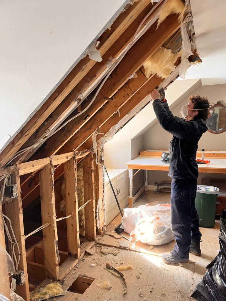 A Paul Davis Restoration of Greater Portland, ME technician removing water-damaged drywall and insulation in Falmouth, ME.