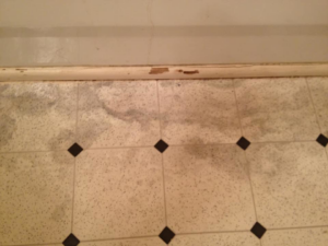 A water-damaged floor and baseboard showing stains and potential mold, addressed by Major Damage in Bentonville, AR.