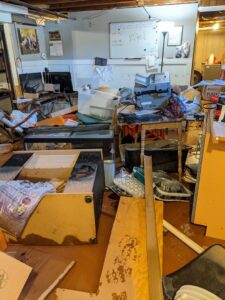 A room with a wet, damaged floor and exposed subfloor, showing water damage by North Shore Restore in Duluth, MN