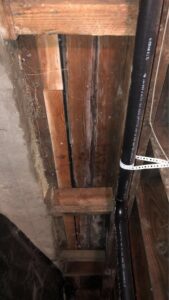 Water-damaged floor joists and subfloor with a black pipe, showing signs of moisture and mold, remediated by Quality Remediation llc in Everett, WA.