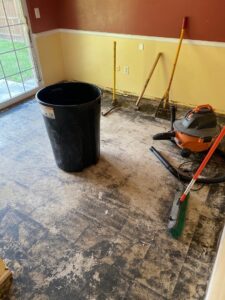 Water-damaged flooring removed from a room, with a wet/dry vacuum and tools, by Incore Restoration Group in Wixom, MI.