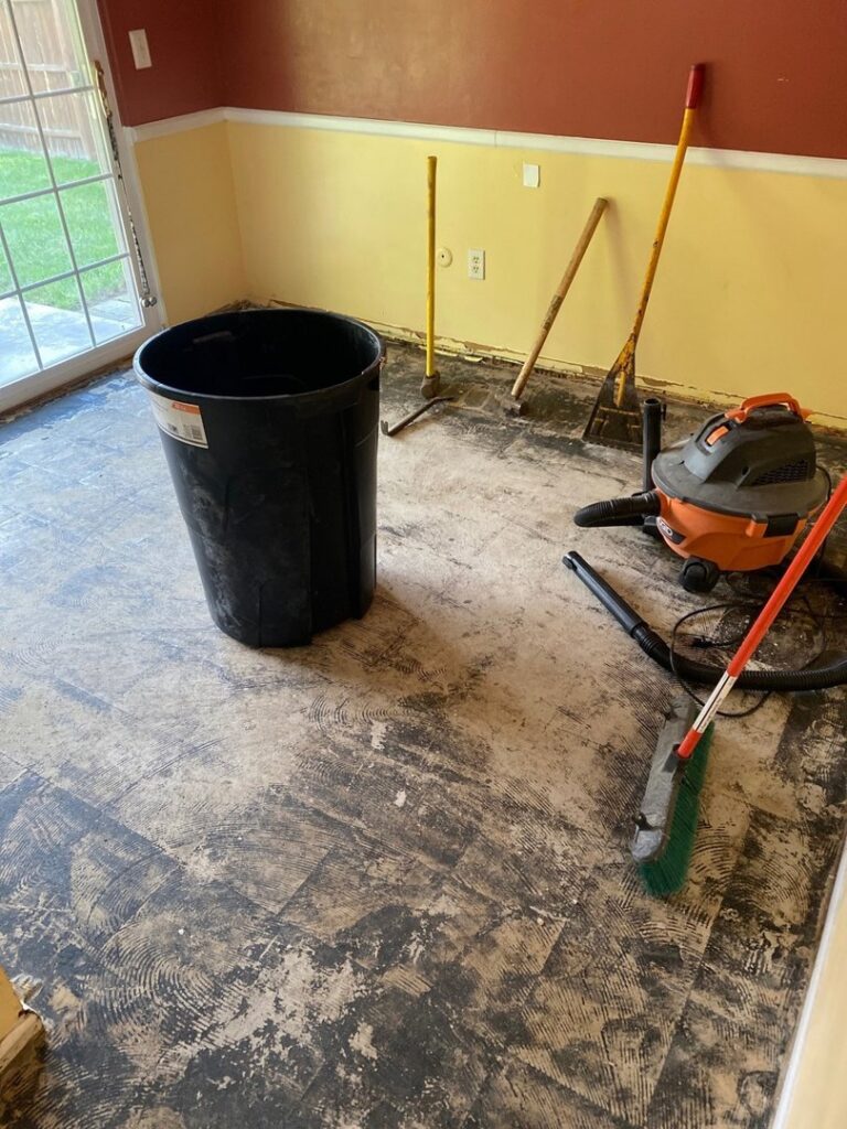 Water-damaged flooring removed from a room, with a wet/dry vacuum and tools, by Incore Restoration Group in Wixom, MI.