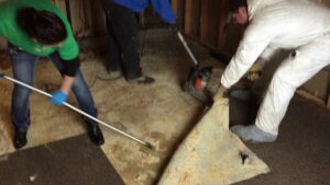 Workers removing water-damaged flooring during a remediation project by Orion Construction in North Canton, OH.