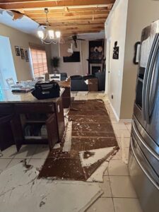 A kitchen showing significant water damage to the ceiling and debris scattered on the floor by Triple Crown Restoration in Covington, KY