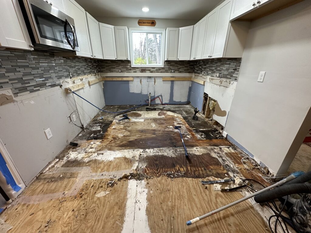 A kitchen undergoing water damage restoration with subfloor exposed and damaged by CleanBright Surface Restoration in Latham, NY.