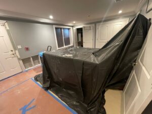 A water-damaged room with removed drywall, covered furniture, and drying equipment by NSH Home Services in Jersey City, NJ.
