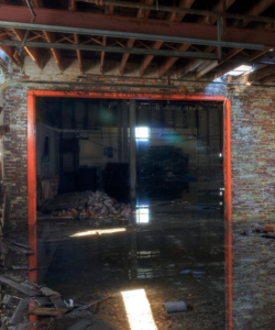 A severely water-damaged room with standing water and debris on the floor, ready for restoration by Beacon Restoration and Cleaning in Birmingham, AL.
