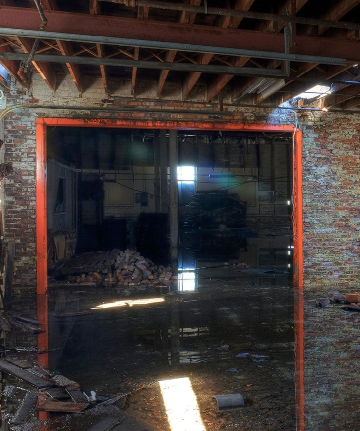 A severely water-damaged room with standing water and debris on the floor, ready for restoration by Beacon Restoration and Cleaning in Birmingham, AL.