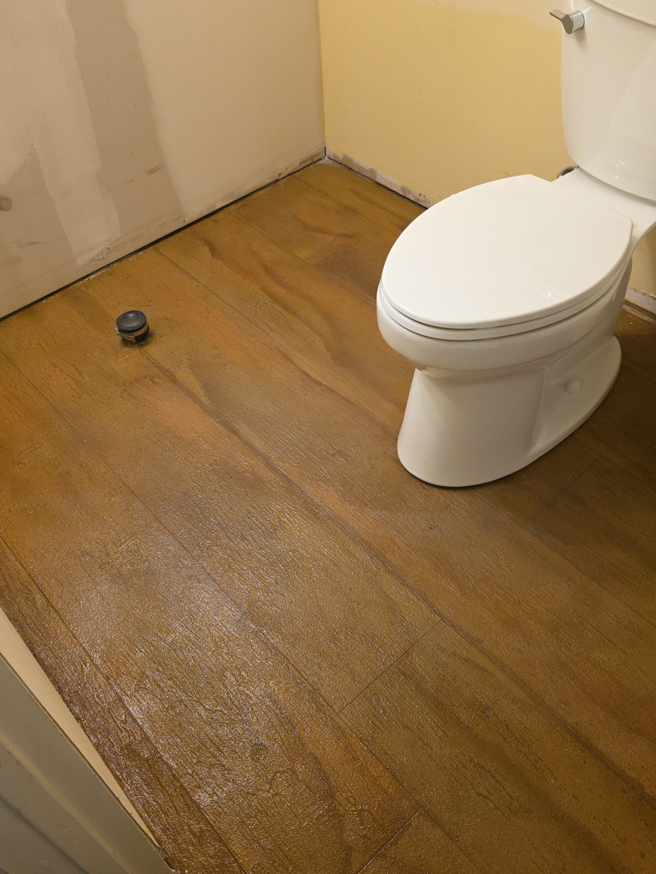 Severely water-damaged subfloor around a toilet, requiring specialist repair from JB'S Home Repair in Manhattan, KS.
