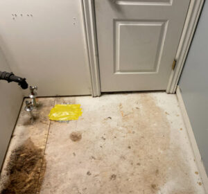 A water-damaged subfloor near a door and pipes, showing the extent of water damage restoration needed by RestoPros of Salt Lake City, UT
