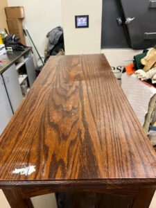 A wooden cabinet with visible water damage on its top surface, handled by Square One Restoration, Inc. in Tempe, AZ.