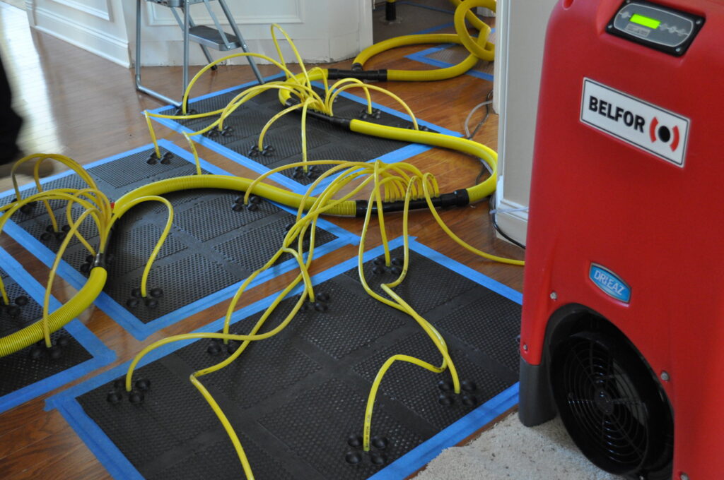 Water extraction and drying equipment on a wooden floor by Belfor Property Restoration, New Orleans, LA