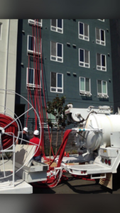 Workers operating large water extraction equipment with hoses extending to a building by San jose water damage in San Jose, CA