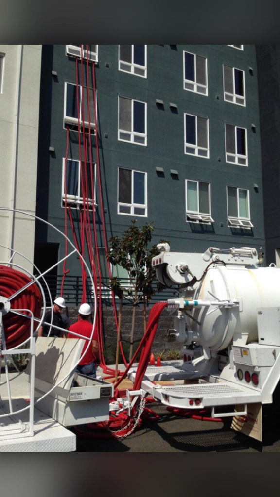 Workers operating large water extraction equipment with hoses extending to a building by San jose water damage in San Jose, CA